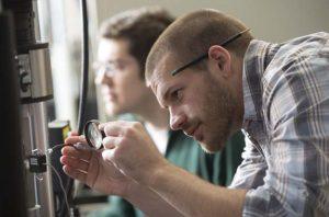 Researchers adjusting materials testing equipment in a laboratory