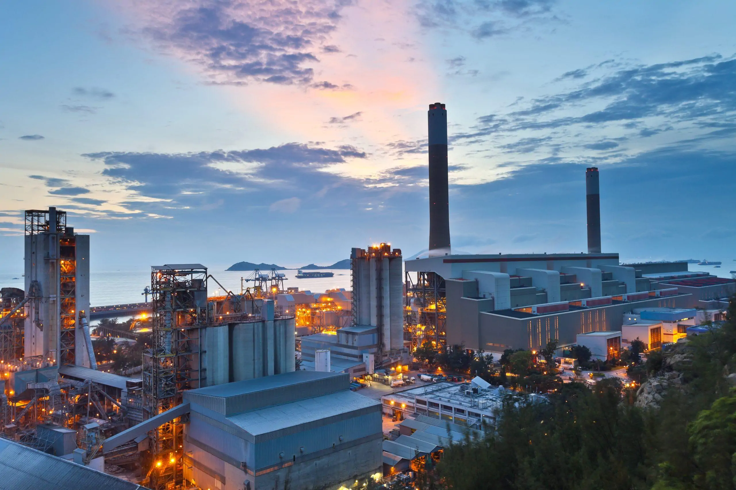Power generation plant with tall exhaust stacks illuminated at dusk